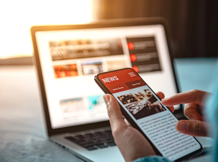 Une personne tient un smartphone devant un ordinateur
