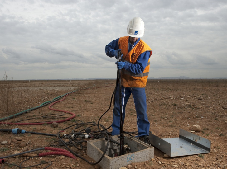 Un technicien sort une pompe d'un puits de captage d'eau, sur le site du chantier de réhabilitation