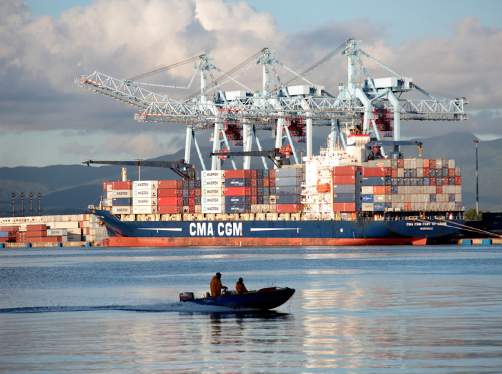 Une vedette passe devant un navire de l'armateur CMA-CGM dans le Grand Port Maritime de la Martinique.