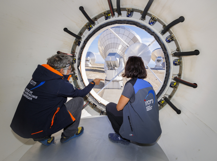 Discussion entre scientifiques au centre de la parabole d'une antenne de l'observatoire NOEMA