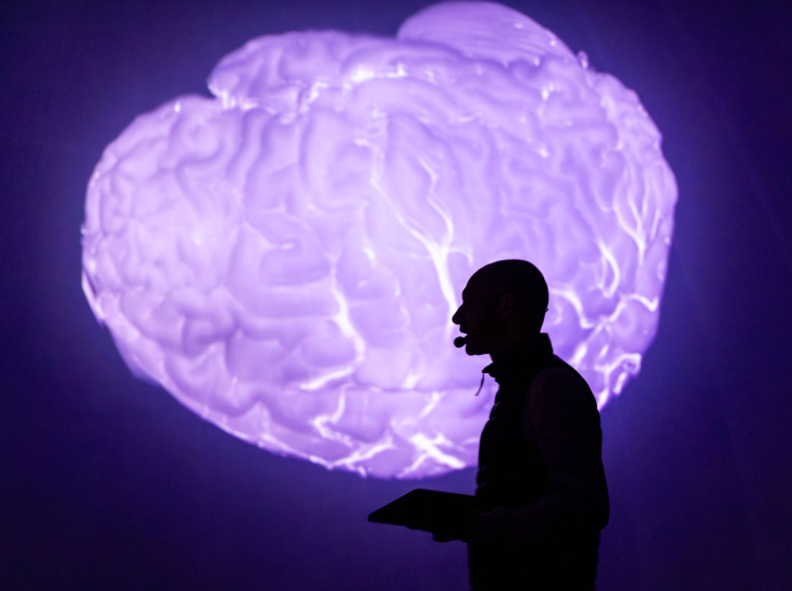 Silhouette d'un chercheur sur fond de cerveau luminescent