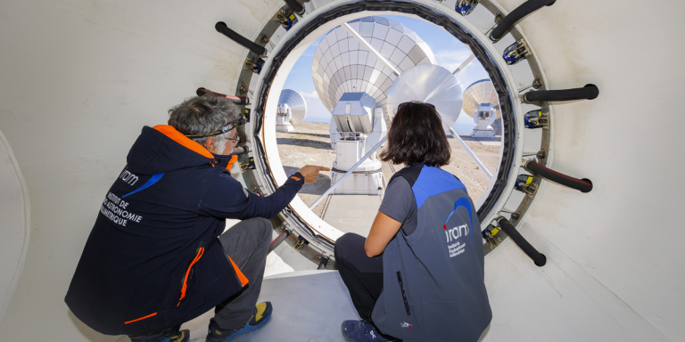 Discussion entre scientifiques au centre de la parabole d'une antenne de l'observatoire NOEMA