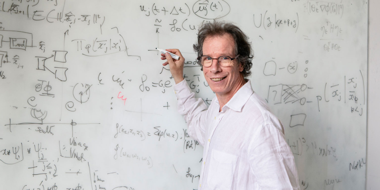 Portrait de Stéphane Mallat, médaille d'or CNRS 2025, devant un tableau couvert d'équations mathématiques