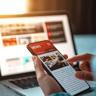 Une personne tient un smartphone devant un ordinateur