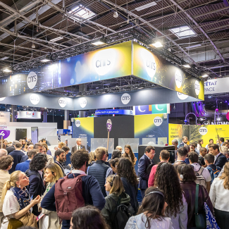 CNRS stand at VivaTech 2024 ; indoors during the day, a crowd of people are walking in front of the stand, we can see the ceiling with several metal structures and square windows