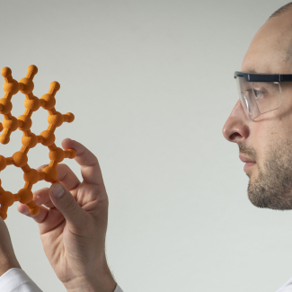 Homme regardant un modèle moléculaire fabriqué par impression 3D permettant de comprendre la stéréochimie.