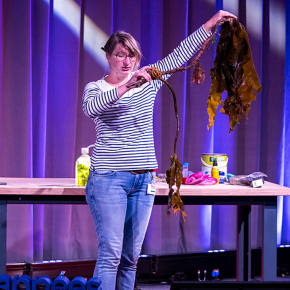 Une chercheuse sur la scène de la Cité des sciences montre une algue au public